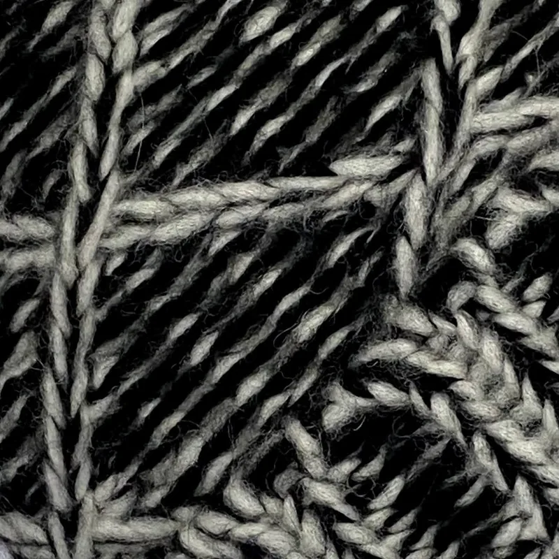 Detalle del punto: rombos en relieve, tejidos en hilo grueso jaspeado en negro y crudo.