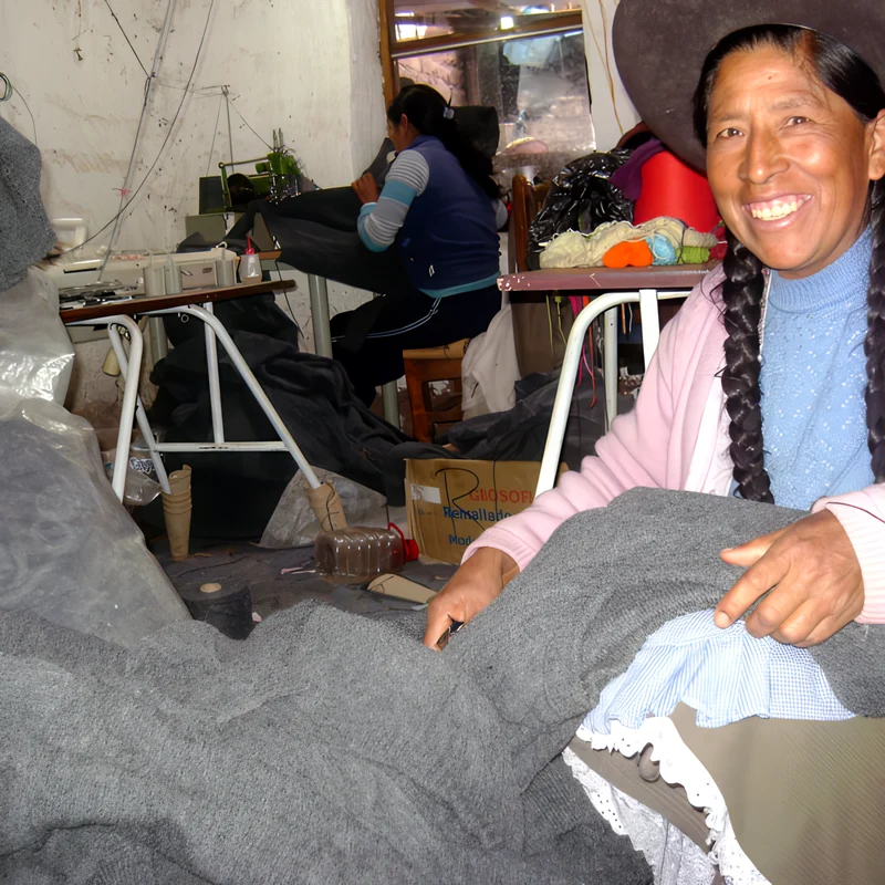 Tejedora del taller sonriendo, revisando una prenda.